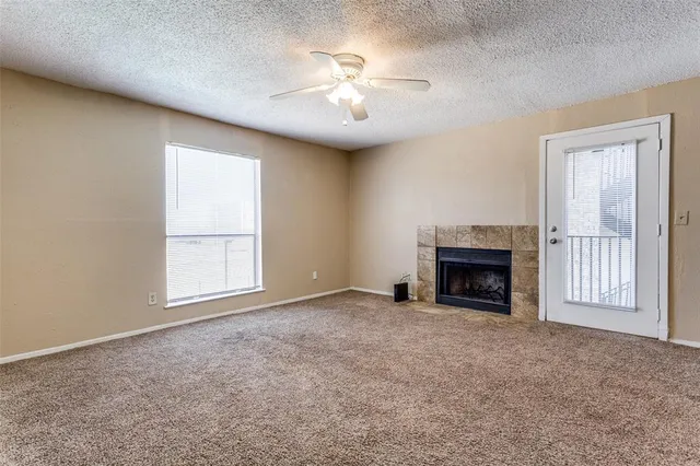 an empty room with windows and fireplace
