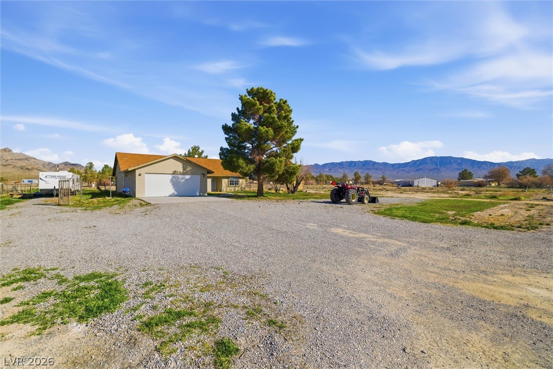 2780 West Simkins Road Pahrump, NV 89060 - Photo 2 of 40 A desert oasis with a spacious gravel driveway, offering mountain vistas and a home with an attached garage.