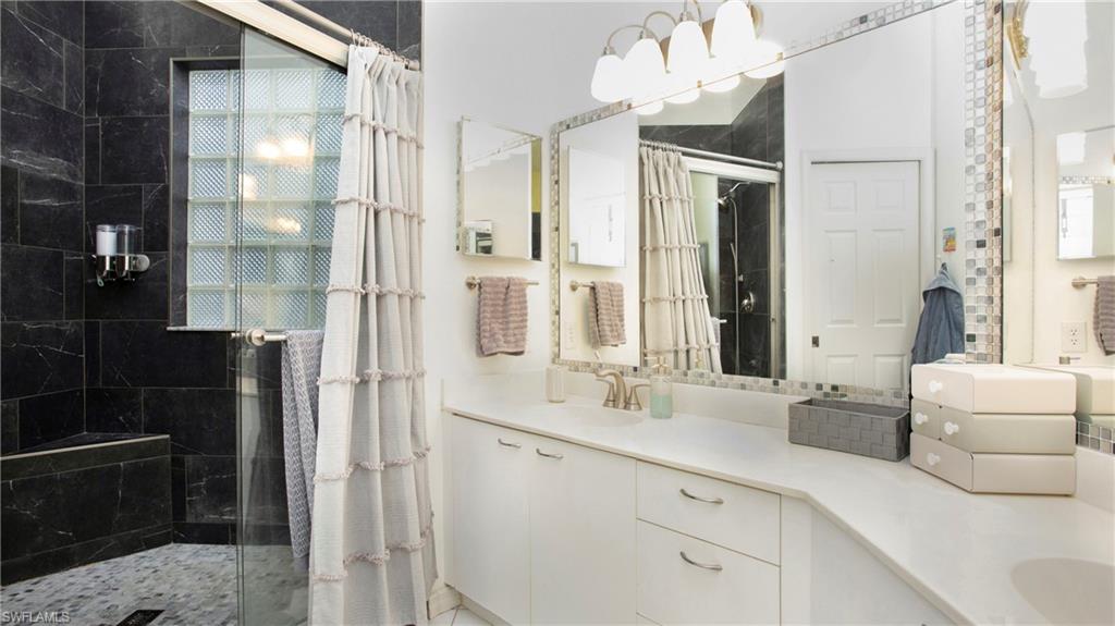 96 Silver Oaks Circle, Unit 1202 Naples, FL 34119 - Photo 11 of 30 a bathroom with a double vanity sink mirror and shower