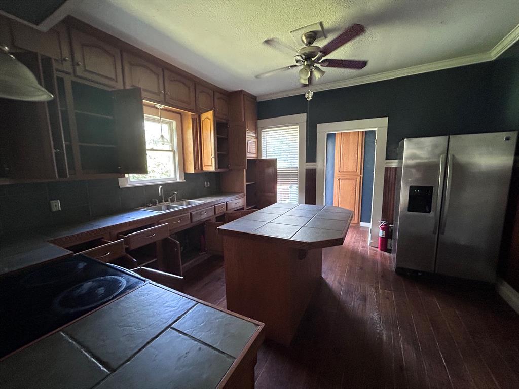 116 Gas Plant Road Doyline, LA 71023 - Photo 14 of 19 Kitchen featuring wood-finish flooring, wood cabinetry, built-in dual basin sink, tile countertops, and a ceiling fan