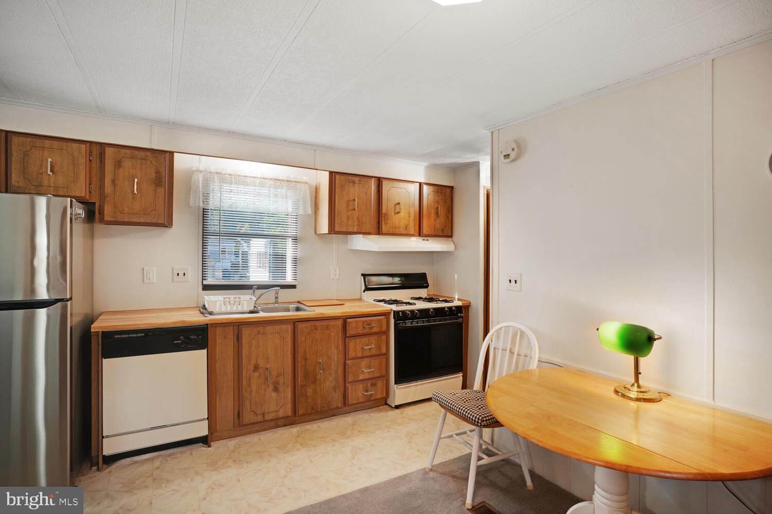 34 Holly Road West Creek, NJ 08092 - Photo 15 of 28 a kitchen with stainless steel appliances granite countertop a sink a stove a refrigerator a microwave a dining table and chairs with wooden floor