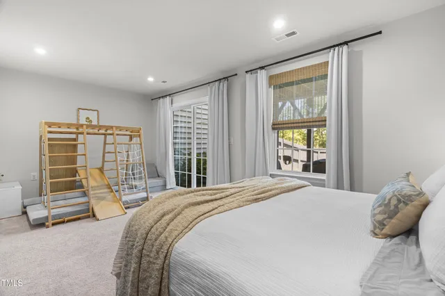 a bed sitting in a spacious bedroom next to a window