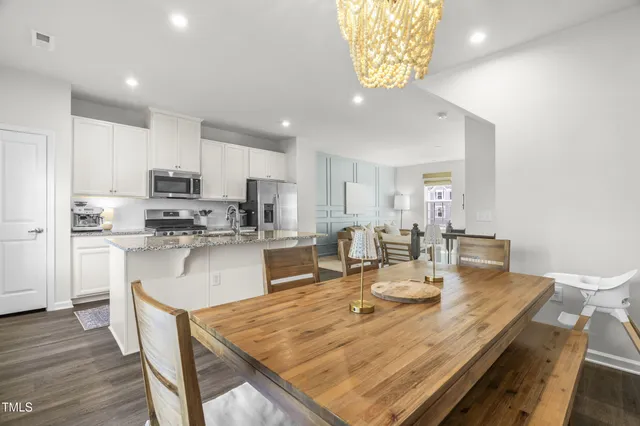 a room with stainless steel appliances kitchen island granite countertop a dining table chairs and granite counter tops