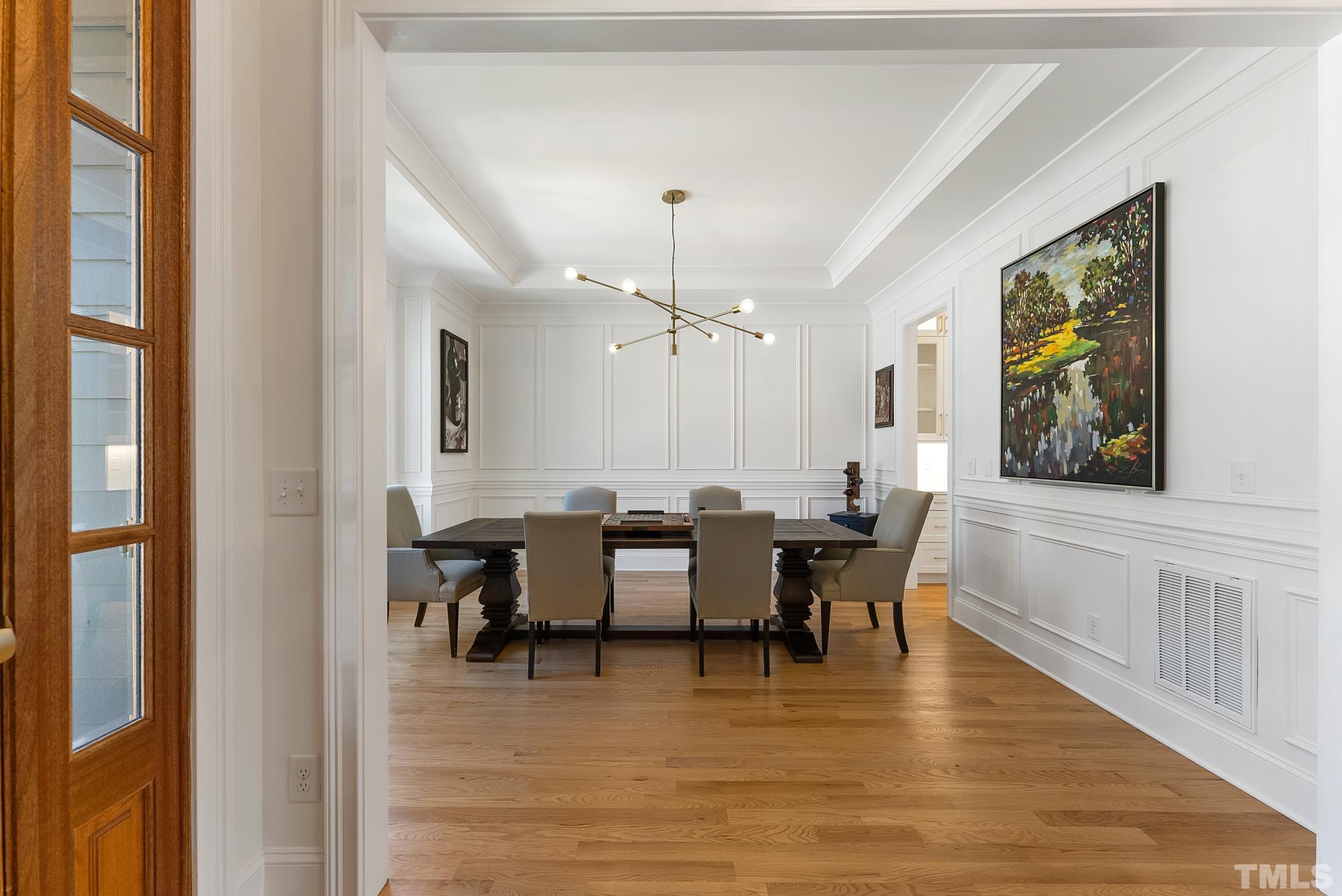 3401 Lewis Farm Road Raleigh, NC 27607 - Photo 5 of 75 a dining room with wooden floor a chandelier a glass table and chairs