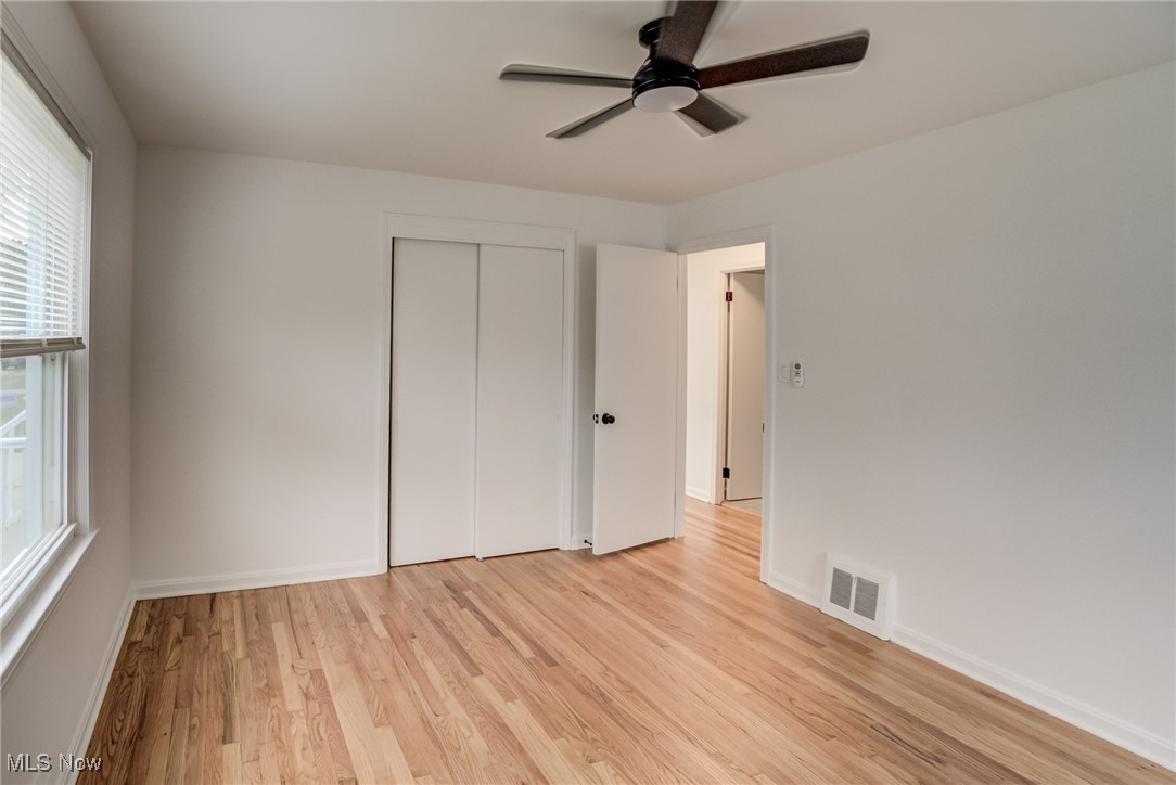 5395 Summit Road Cleveland, OH 44124 - Photo 11 of 28 Unfurnished bedroom with a closet, multiple windows, light hardwood / wood-style floors, and ceiling fan