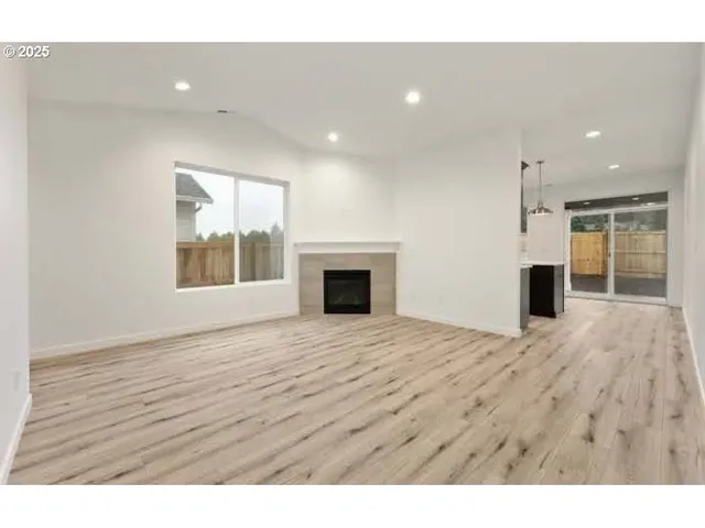 a view of empty room with wooden floor and fireplace