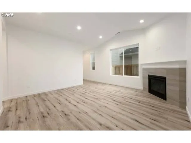a view of empty room with wooden floor and fireplace