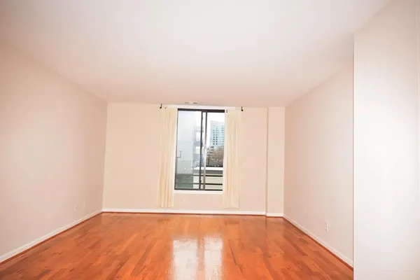 a view of an empty room with wooden floor and a window