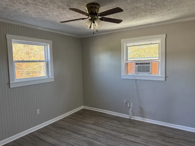 a view of an empty room with window and wooden floor
