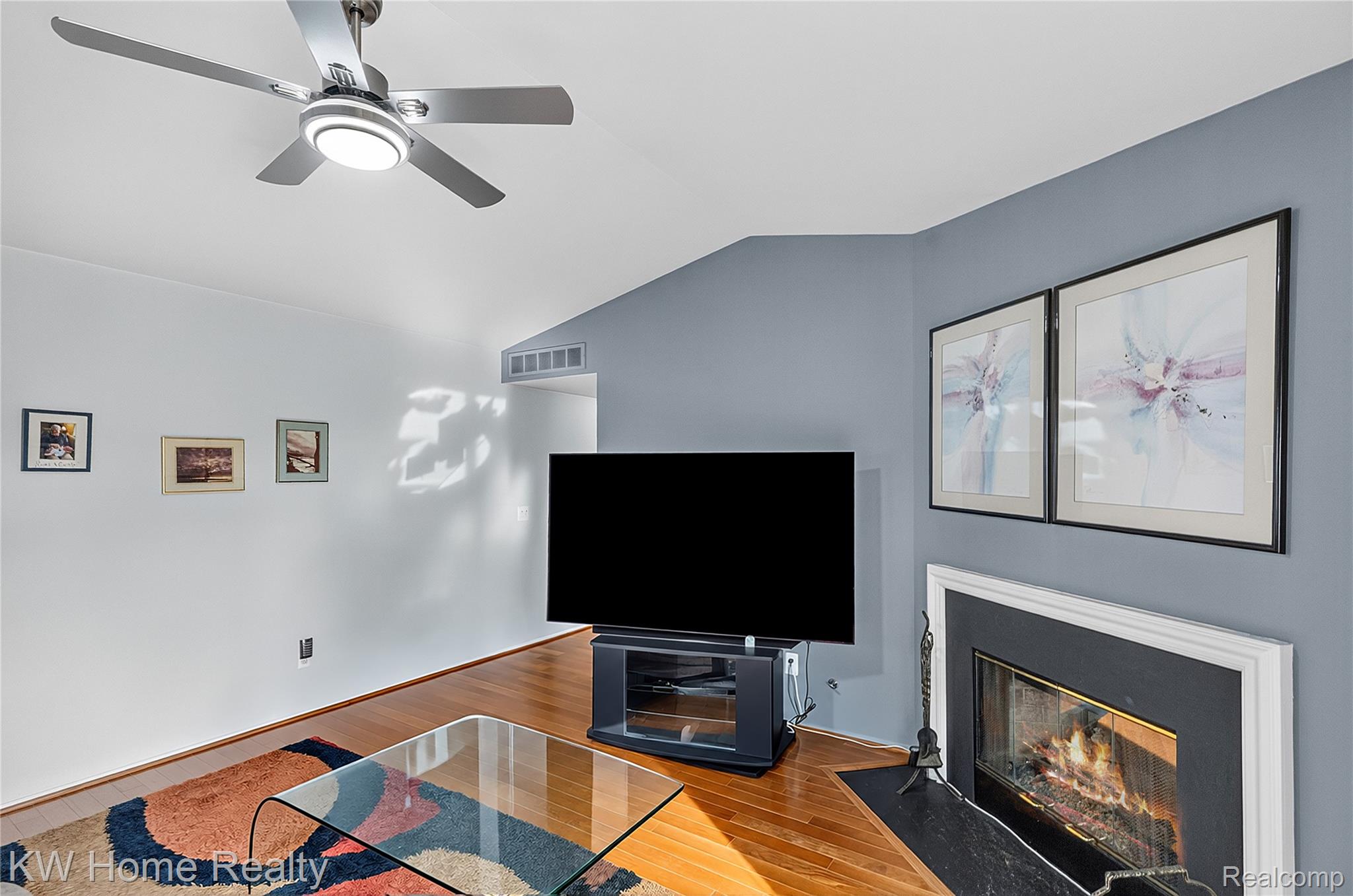 3216 High Pointe Ridge Road Lake Orion, MI 48359 - Photo 5 of 24 The Living Room features a vaulted ceiling featuring a ceiling fan with integrated lighting, solid wood flooring, and a gas fireplace