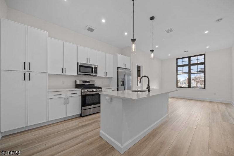 1 Union Avenue, Unit 207 Cresskill, NJ 07626 - Photo 19 of 49 a large kitchen with granite countertop a stove a sink dishwasher and a refrigerator with wooden floor