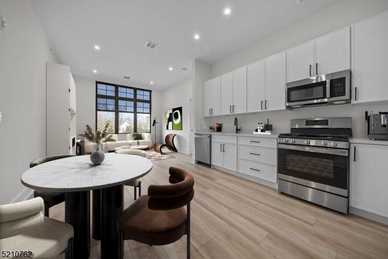 1 Union Avenue, Unit 207 Cresskill, NJ 07626 - Photo 23 of 49 a kitchen with stainless steel appliances a dining table chairs stove and white cabinets