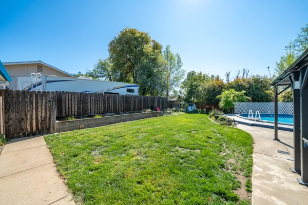 a view of pool with lawn chairs and wooden fence
