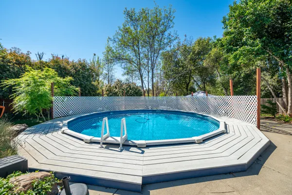 a view of a white house with a large tree and a yard with wooden fence
