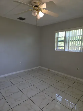 en empty room with windows and chandelier fan