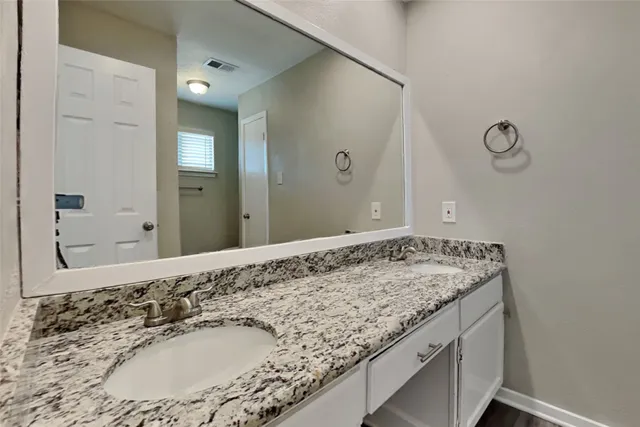 a bathroom with a granite countertop sink and a mirror