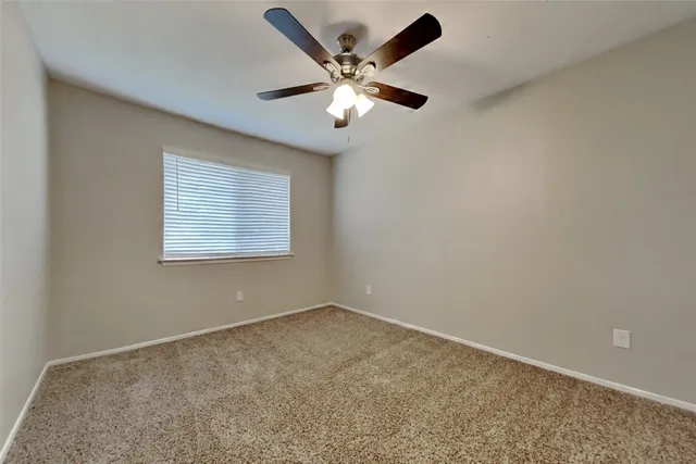 an empty room with ceiling fan and window