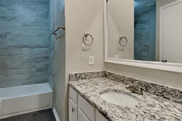 a bathroom with a granite countertop sink and a mirror
