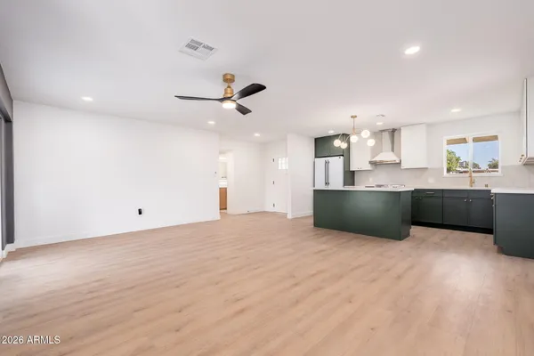 a large kitchen with stainless steel appliances a large counter top a sink a refrigerator and a window