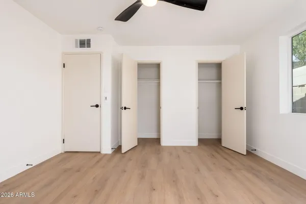 an empty room with ceiling fan and window