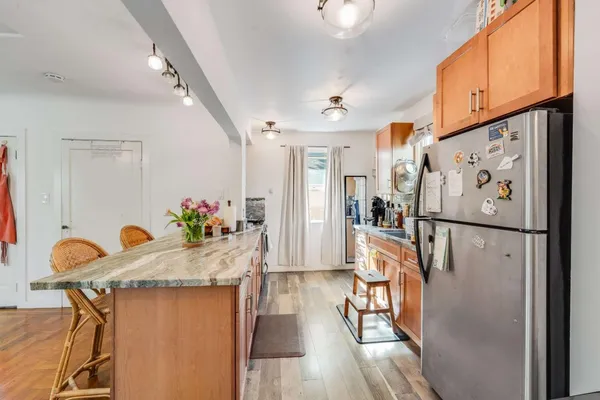 a kitchen with granite countertop a refrigerator a stove a dining table and chairs with wooden floor