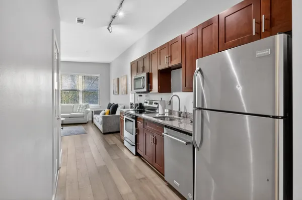 a kitchen with stainless steel appliances a refrigerator a sink a stove top oven a counter space and cabinets