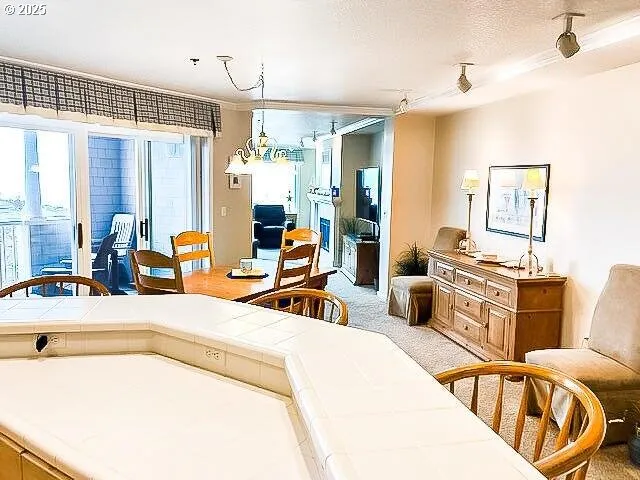 a living room with a dining table chairs and a kitchen view