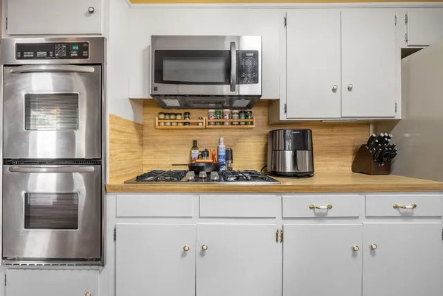a kitchen with stainless steel appliances granite countertop a sink and white cabinets