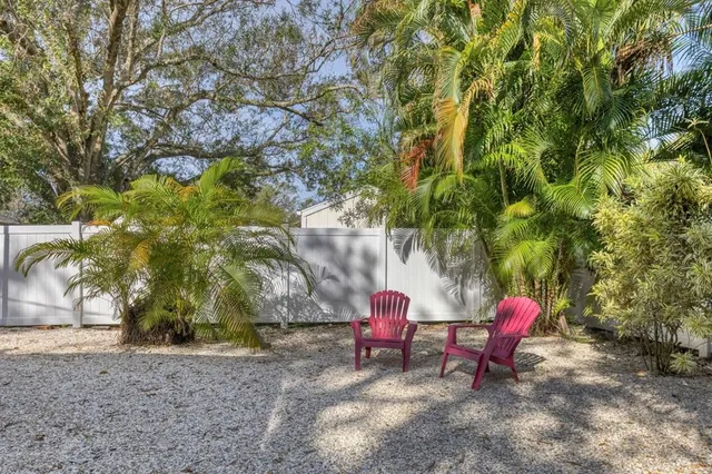 a view of a patio with table and chairs under an umbrella with a large tree