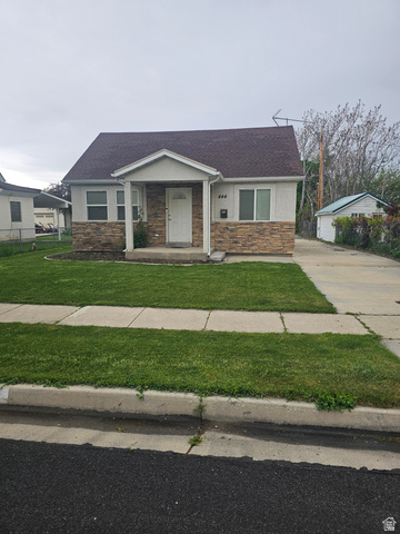 Ranch-style residence featuring a covered front porch, stone veneer facade, and a paved driveway leading to a detached outbuilding