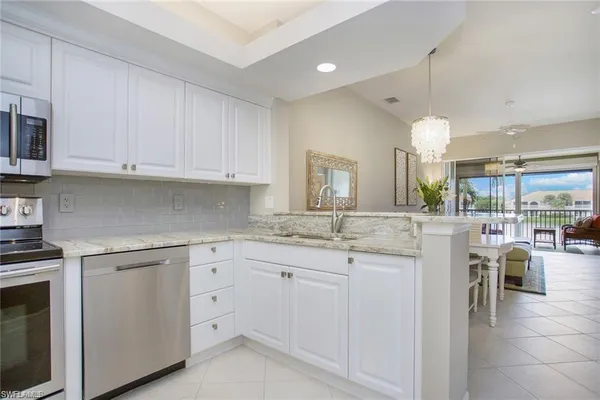 a kitchen with white cabinets and sink