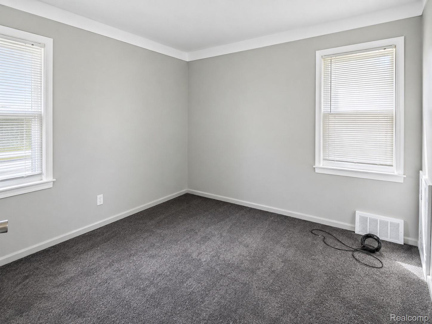 13590 Rutherford Street Detroit, MI 48227 - Photo 9 of 10 Light gray wall paint, dark gray carpeting, white trim, and two windows with blinds