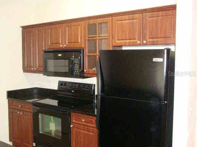 3725 Conroy Road, Unit 2135 Orlando, FL 32839 - Photo 3 of 14 a kitchen with granite countertop a refrigerator stove and cabinets