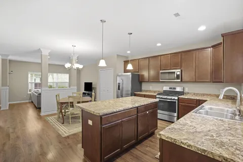 a kitchen with stainless steel appliances granite countertop a stove top oven a refrigerator a sink and a island