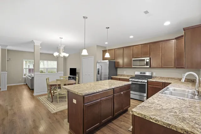 a kitchen with stainless steel appliances granite countertop a stove top oven a refrigerator a sink and a island