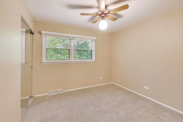 an empty room with a window and a fan