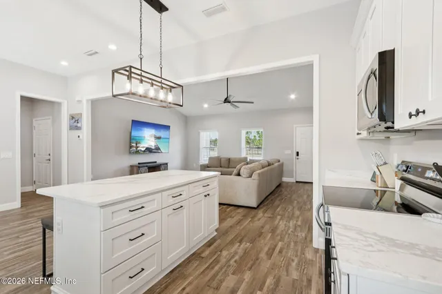 a kitchen with stainless steel appliances granite countertop a refrigerator a stove a sink dishwasher a refrigerator white cabinets and wooden floor