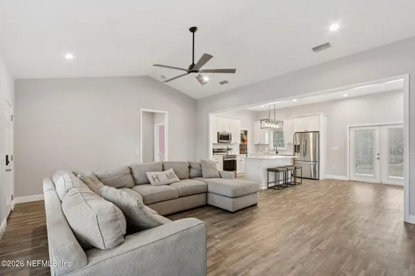 a kitchen with stainless steel appliances white cabinets and a stove a sink and dishwasher with wooden floor