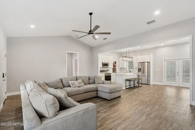 a kitchen with stainless steel appliances white cabinets and a stove a sink and dishwasher with wooden floor