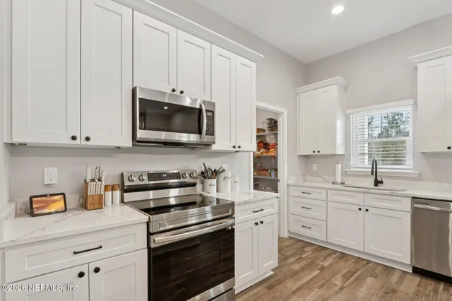 a kitchen with white cabinets and stainless steel appliances