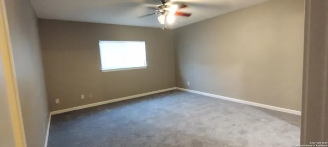 an empty room with a chandelier fan and windows