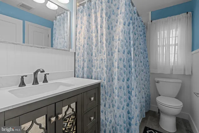 a bathroom with a granite countertop sink a toilet and a mirror