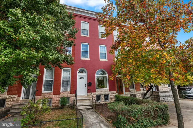 a view of a brick building with floor to ceiling windows and trees