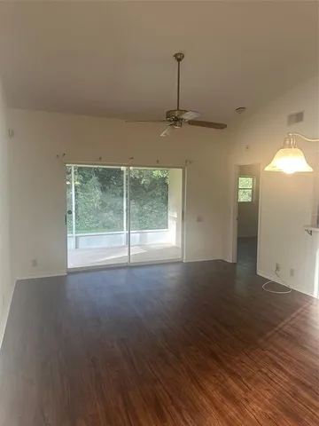 a view of an empty room with window and wooden floor