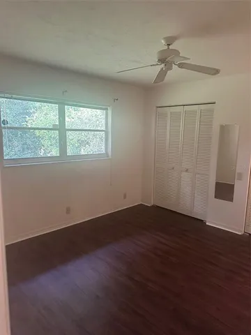an empty room with wooden floor fan and windows