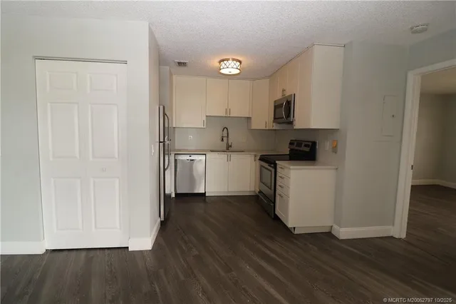 a kitchen with white cabinets and wooden floor