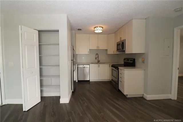 a kitchen with white cabinets and wooden floor