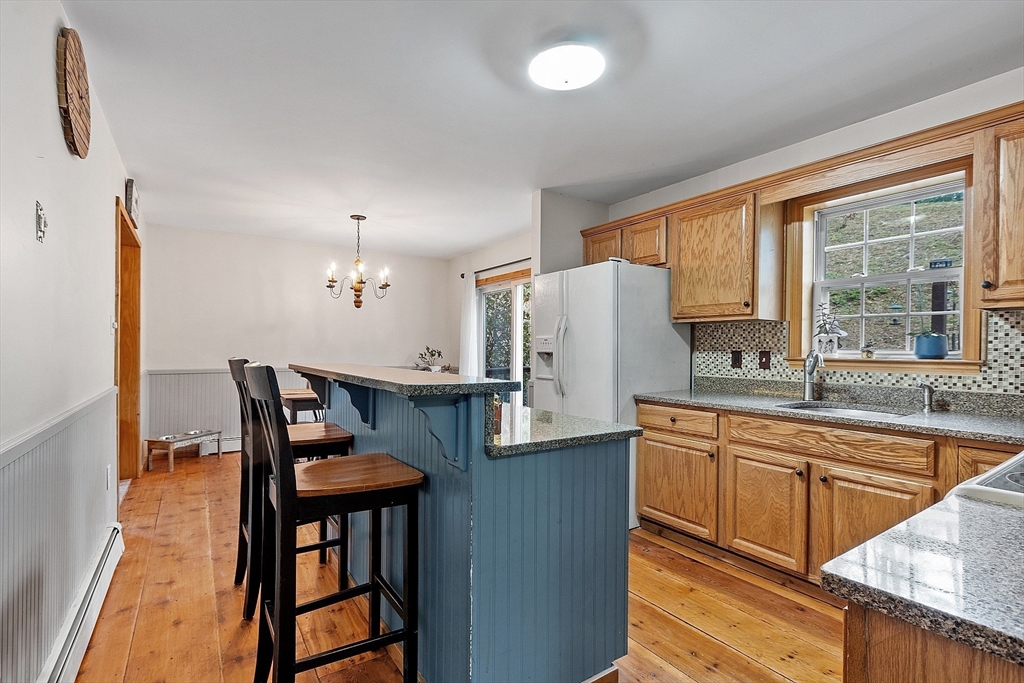 32 East Rindge Road Ashburnham, MA 01430 - Photo 8 of 31 a kitchen with stainless steel appliances granite countertop a sink a stove a refrigerator a dining table and chairs with wooden floor