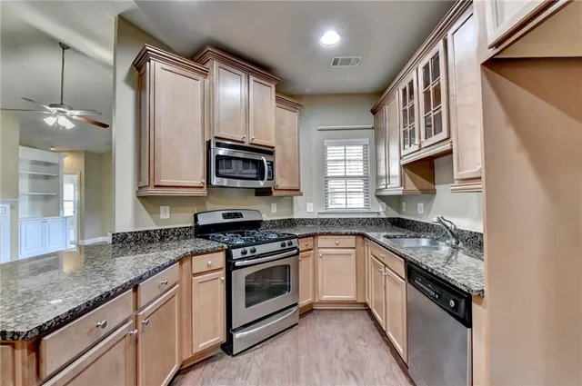 a kitchen with stainless steel appliances granite countertop a sink stove and cabinets
