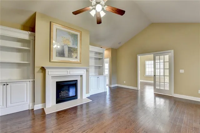 a view of a livingroom with a fireplace a ceiling fan and windows